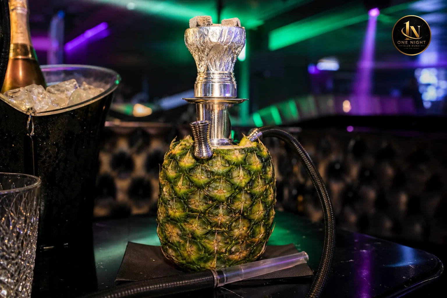 Premium fruit-head shisha setup with fruit bowl base on a nightclub table. Photorealistic close-up photo of a premium fruit-head shisha pipe with a real pineapple or melon bowl base sitting on a polished black nightclub table, condensation