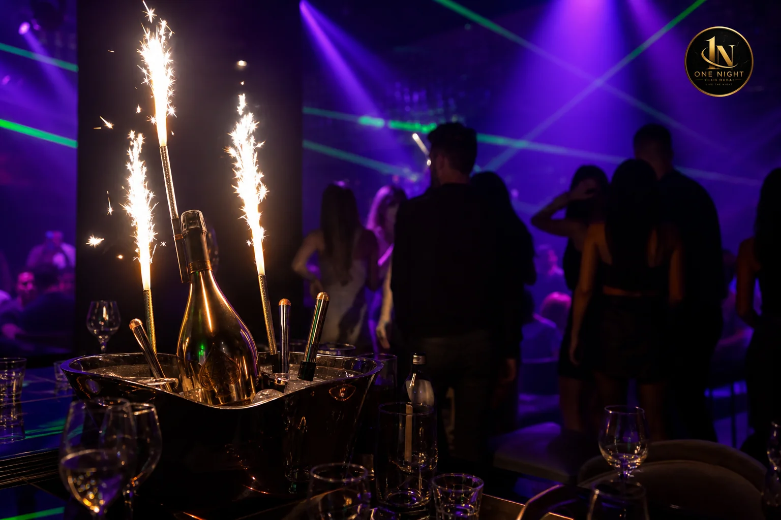 Group celebrating at a mid-tier nightclub table with bottle service and sparklers near the dance floor. Photorealistic photo of a lively nightclub scene showing a reserved table close to the dance floor with a bottle service presentation