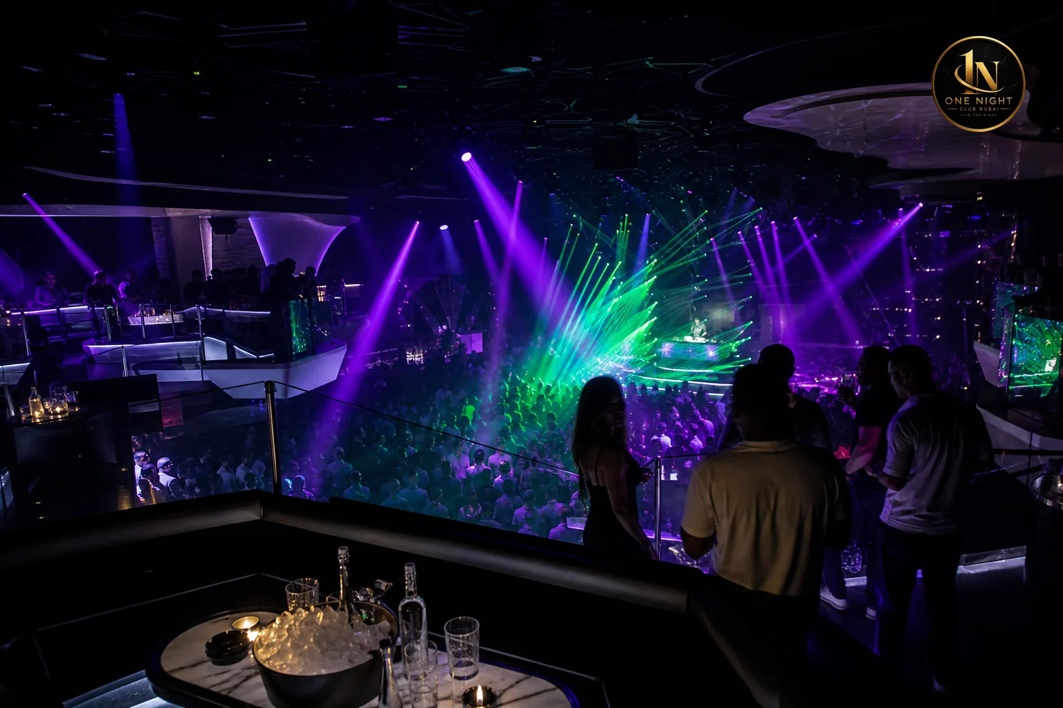 Comparison of floor-level vs raised VIP seating inside a Dubai nightclub. Photorealistic photograph of a modern Dubai nightclub interior showing a raised VIP platform table overlooking a busy dance floor below, black and white color scheme