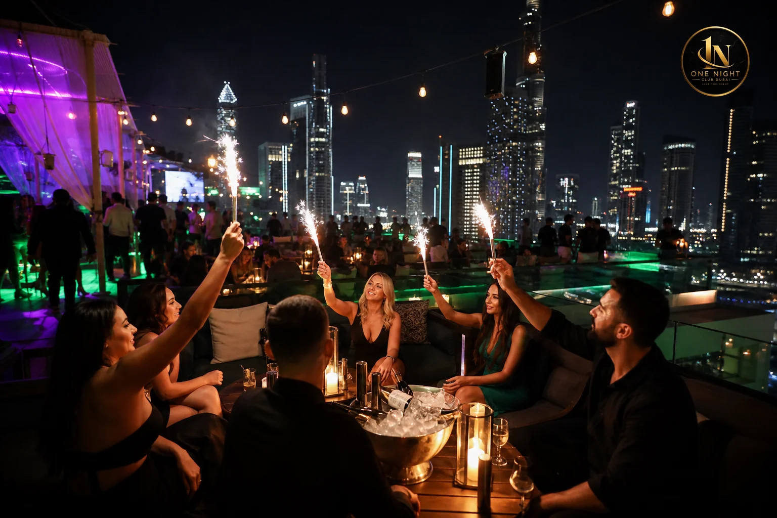 Rooftop nightclub scene with open-air skyline view contrasted against indoor VIP table seating for a birthday celebration. Photorealistic photograph of an open-air rooftop nightclub terrace in Dubai at night, skyline of illuminated towers